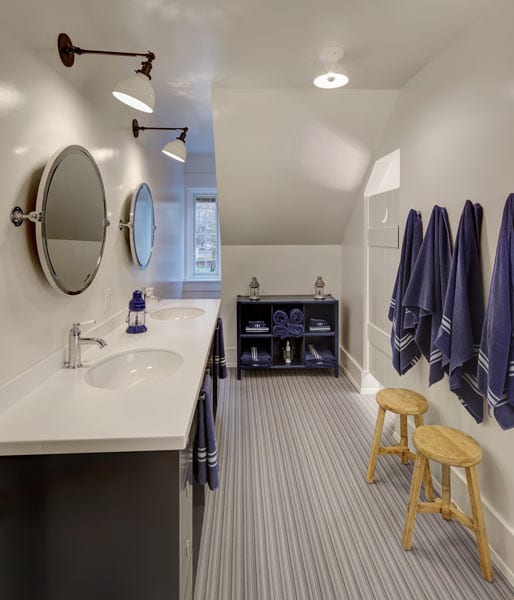bathroom with two sinks and mirrors with towels on hooks