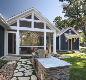 picture of a blue home with large windows with a grill outside
