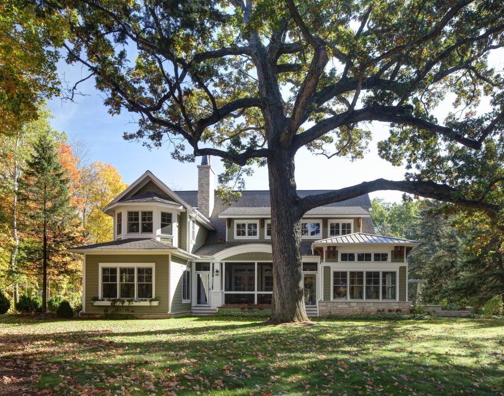 picture of a green home with a tree in front of it