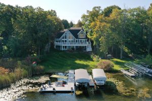 picture of a blue house on a lake with a dock and boats