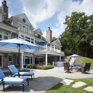picture of a house exterior with blue chairs and umbrellas