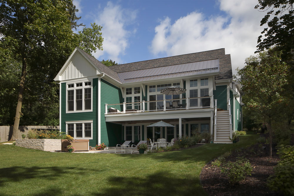 green home exterior with an outdoor porch and patio