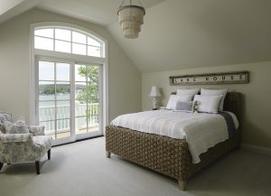 image of a cream bedroom with a bed, chair, and balcony